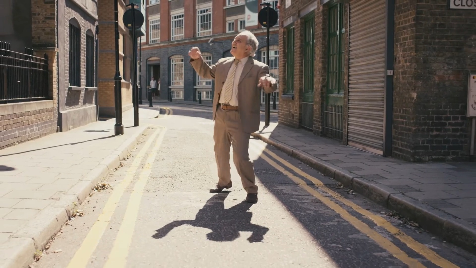 Elderly man joyfully dancing in a sunlit urban street, captured in a Biteable video.