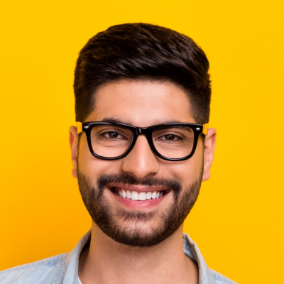 Portrait of a smiling man with beard and glasses, against a yellow background.